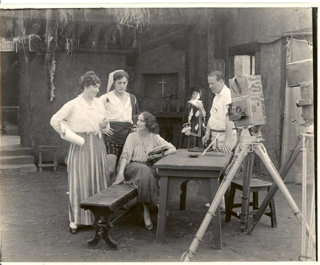 A black and white image of early 20th Century filmmaker Lois Weber and actors shooting a movie. 
