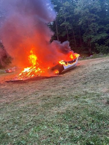 small boat and pile of trash on fire in a field
