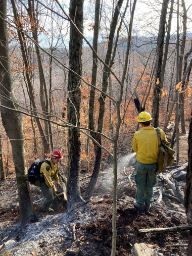 Rangers using extinguishers to control fire in the woods