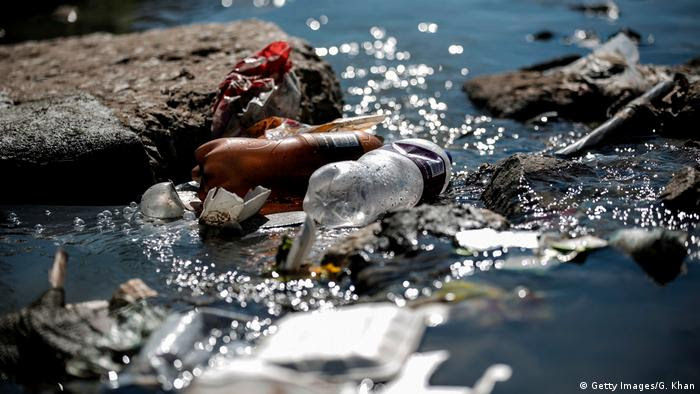 Garrafas de plástico e outros lixos plásticos no leito de um rio