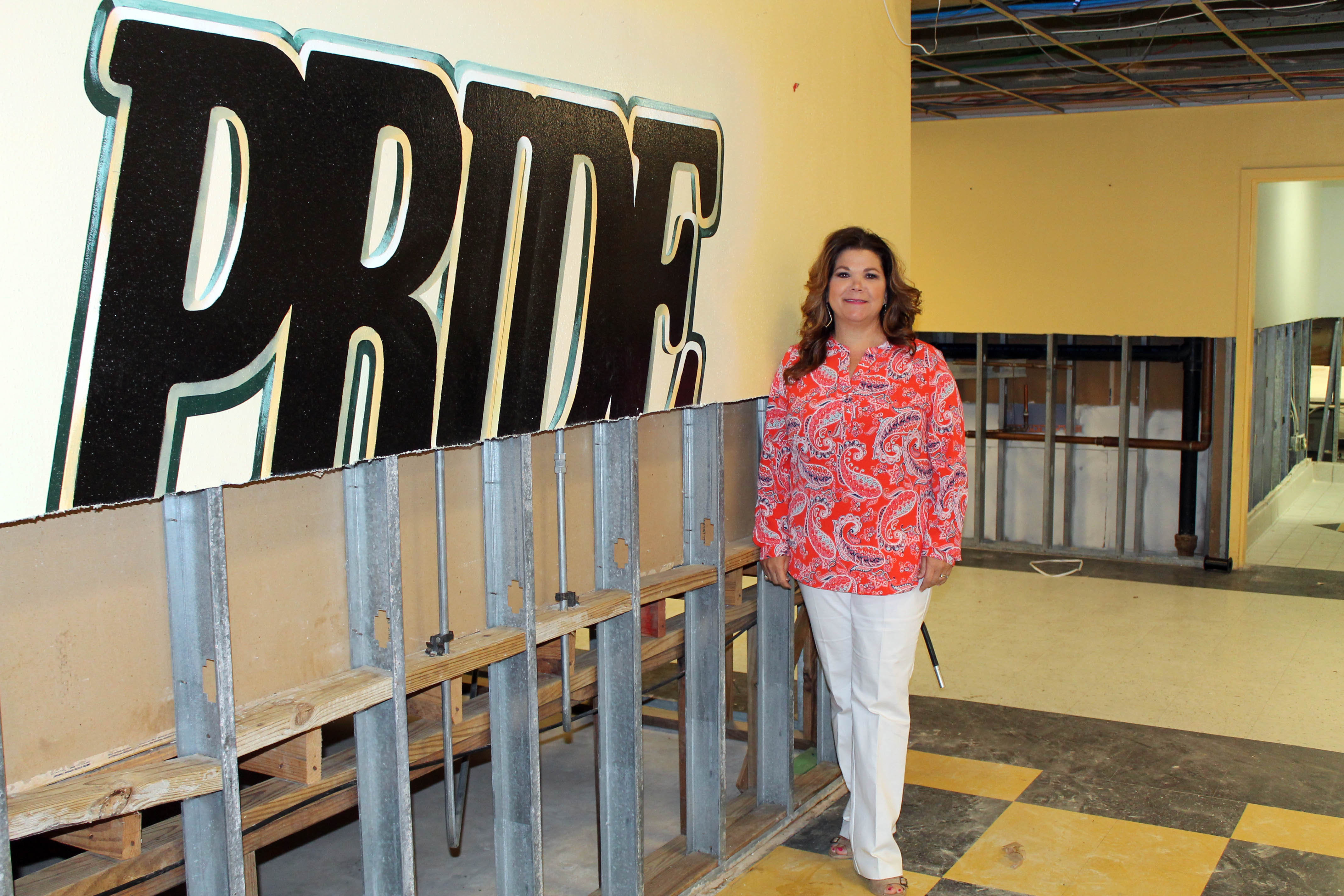 Mia Edwards next to a gutted wall with the word "Pride"