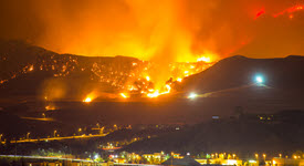 wildfire racing down mountain towards a city