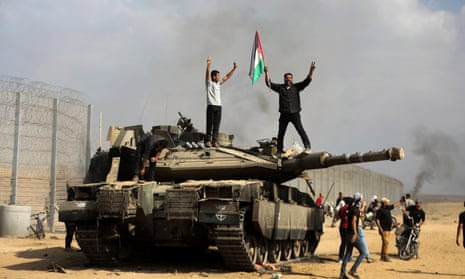 Palestinians with a destroyed Israeli tank at the Gaza Strip fence east of Khan Younis on 7 October