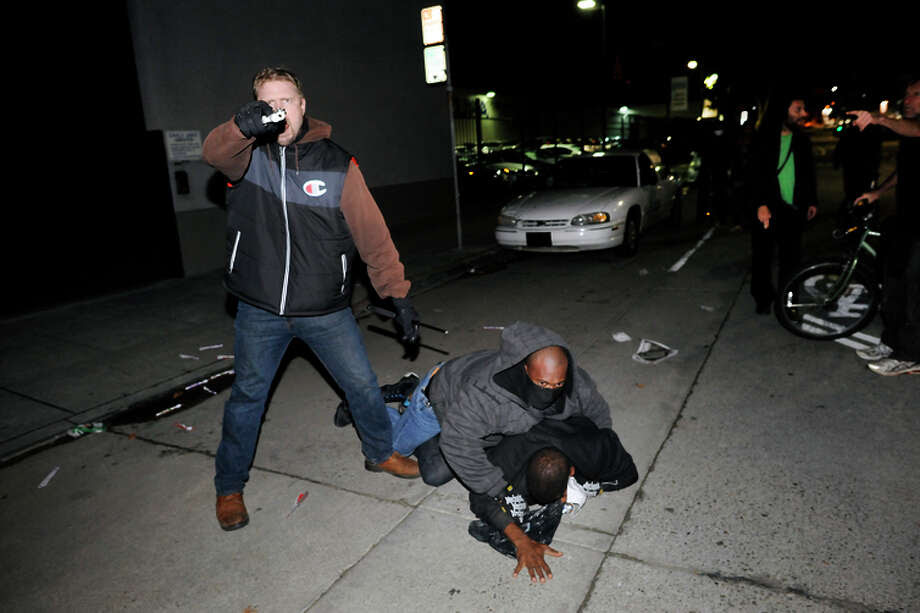 An undercover officer points his gun at the crowd while his partner subdues a protester who struck him in the back of the head, as demonstrations continue for a fifth night in Oakland on Wednesday, Dec. 10, 2014. Photo: Michael Short / Special To The Chronicle / ONLINE_YES