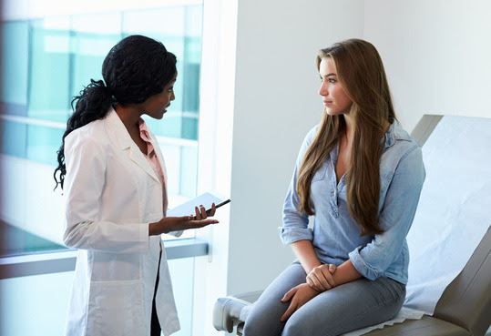 female doctor talking with college age female patient