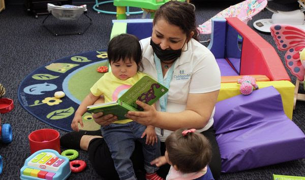 This May 4, 2021, file image shows teacher Graciela Olague-Barrios reading to two infants at Cuidando Los Ninos in Albuquerque, N.M. The charity provides housing, child care and financial counseling for mothers. (AP Photo/Susan Montoya Bryan) ** FILE **