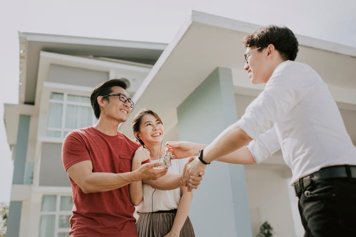A man and woman shaking the hand of their real estate agent.