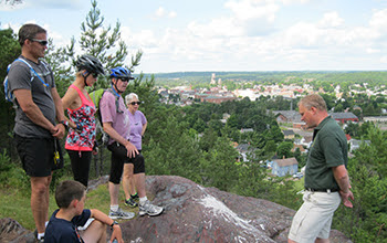 Group of people standing on hilltop listening to DNR staffer speak