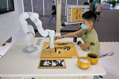 A boy plays Go with a robot in the exhibition hall of SCE 2022, on 21st August 2022, Chongqing, China.