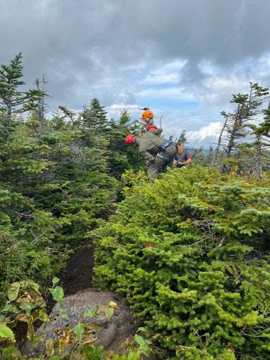 Rangers help put a harness on exhausted hiker during rescue