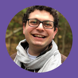 Ami Altzman, white, cis Jewish man, wearing glasses and a scarf, smiling at the camera