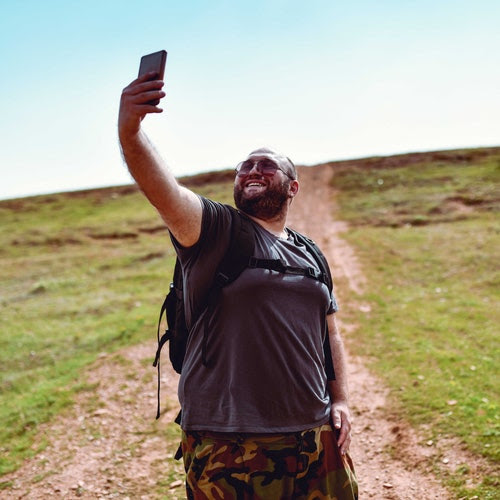 A man takes a selfie while on a hike.