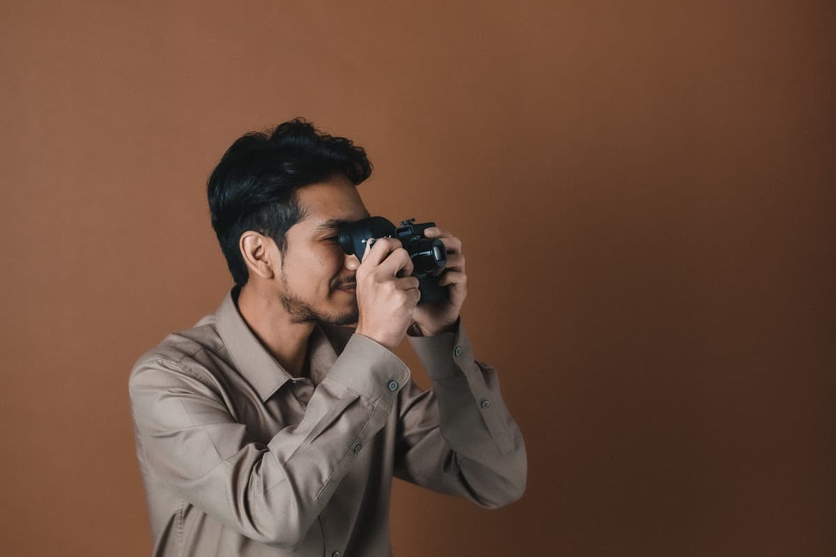 Man seen from side looking through viewfinder on camera