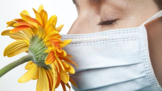 Mujer con mascarilla huele una flor