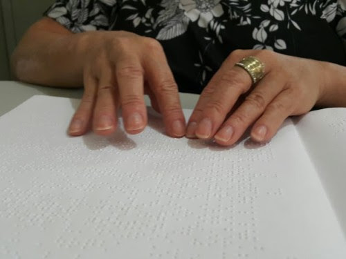 Muher com deficiência visual lê livro em Braille em biblioteca de Taguatinga, no Distrito Federal