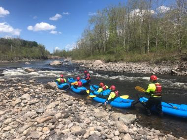 Rangers in blue inflatable kayaks during rescue training on a creek