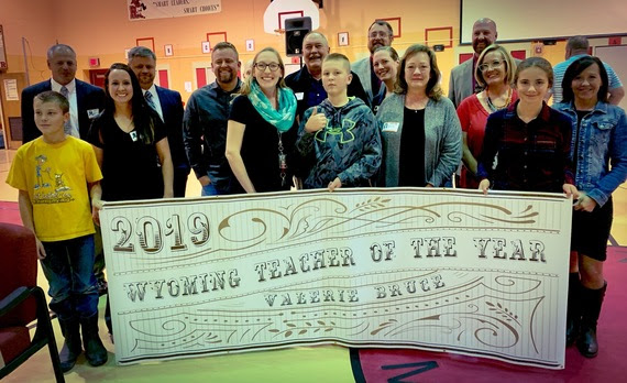 Mrs. Bruce stands with faculty and students from her school behind a banner that reads, "2019 Wyoming Teacher of the Year, Valerie Bruce."