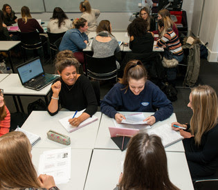 Image of students having group discussions in a seminar room.