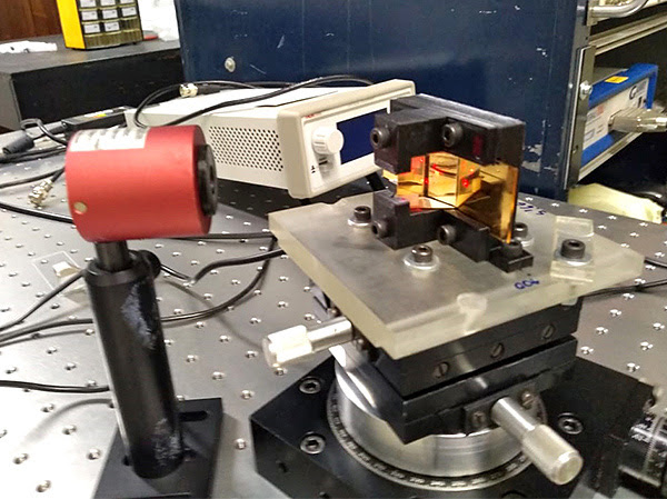 Prisma e lâmina de ouro montados na célula eletroquímica. Os pontos vermelhos na lâmina são a entrada e a saída do feixe de luz laser (Foto: Divulgação)