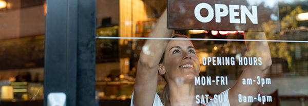 Happy business owner hanging an open sign at a cafe 