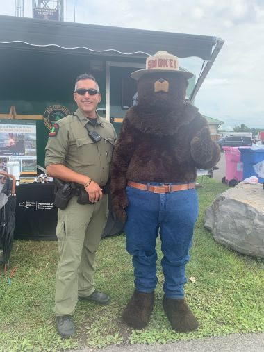 Ranger and Smokey Bear pose for photo in front of DEC booth