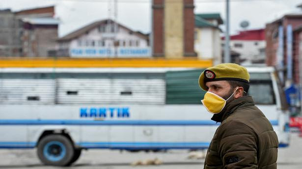 A policeman wearing a face mask stands guard at a road checkpoint in Srinagar on March 25, 2020 during the first day of the 21-day nationwide lockdown . 