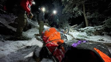 Rangers pull an injured hiker through the woods and snow during a rescue at night