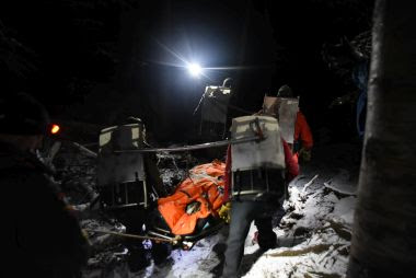 Rangers carry injured hiker out on a snowy trail during a night rescue