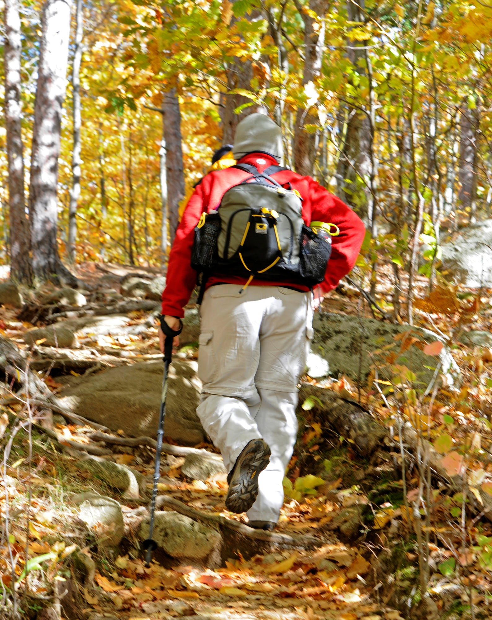 A woman hiking through the colorful leaves of fall.