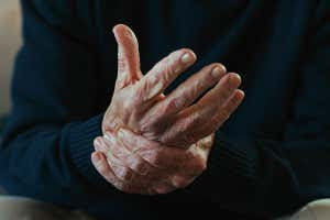 Cropped shot of an unrecognisable man sitting alone at home and suffering from arthritis in his hands - stock photo