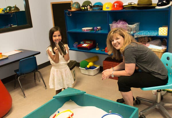 Dee Ray poses with a young girl (not a patient) in a play room at her Texas offices. Many kids who can’t express their emotions in words can do it easily through play. 