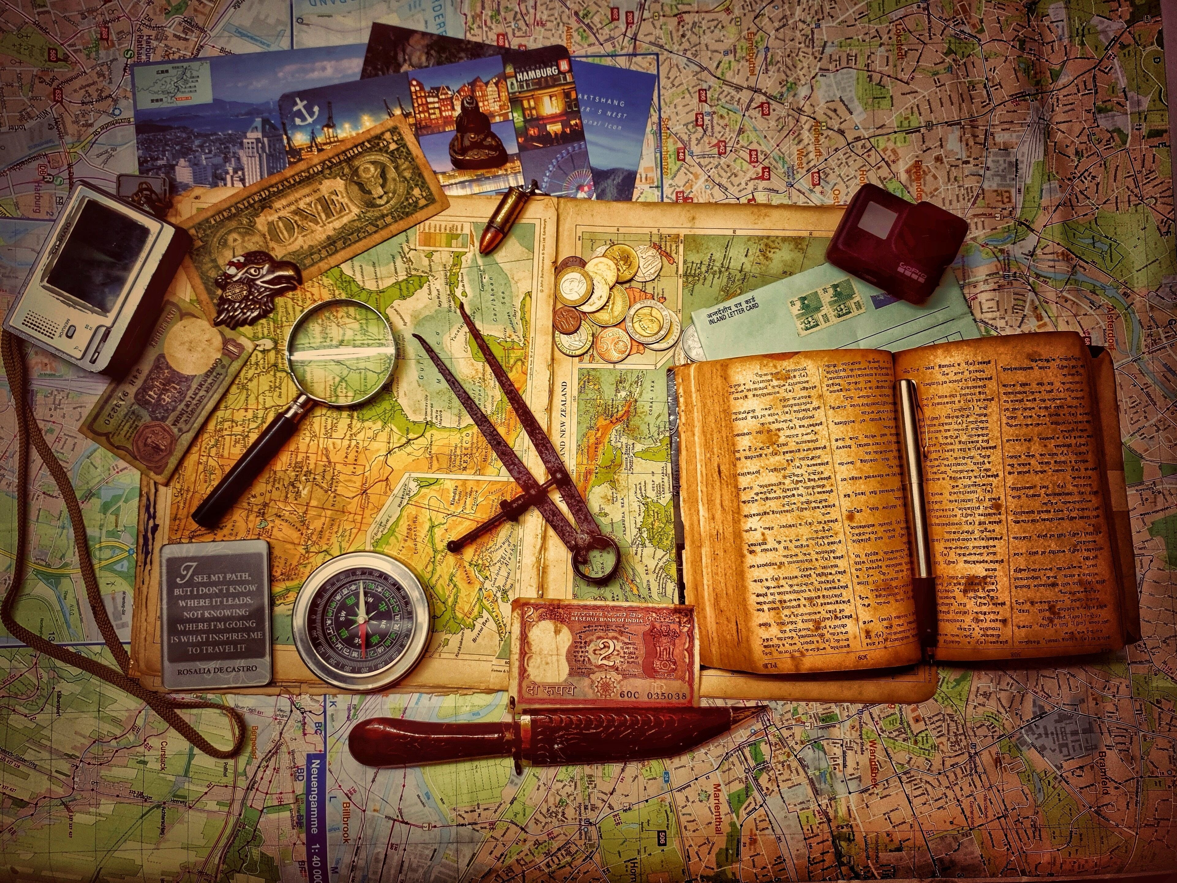 Maps, photos, compass, journal, and other items for planning an adventure. Photo by Suhash Villuri via Unsplash.