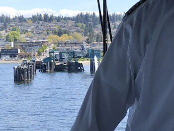 Looking out the front window of a ferry from the pilothouse with a crewmembers left shoulder in view