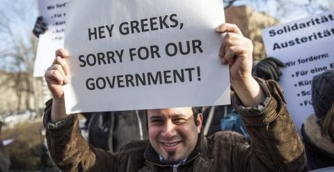 "Hey griegos, perdón por nuestro Gobierno". Un manifestante sujeta un cartel durante una protesta frente al Ministerio de Finanzas alemán. - EFE