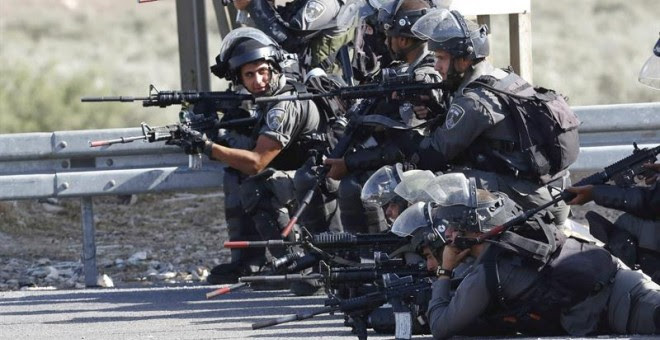 Soldados israelíes toman posiciones frente a manifestantes palestinos durante los enfrentamientos en el puesto de control de Howara, cerca de Nablus, Cisjordania.-  EFE / EPA / ALAA Badarneh