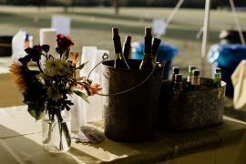 Vase of flowers next to bucket of wine bottles.