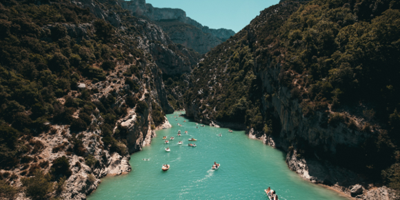 an image of people kayaking in a river between mountains