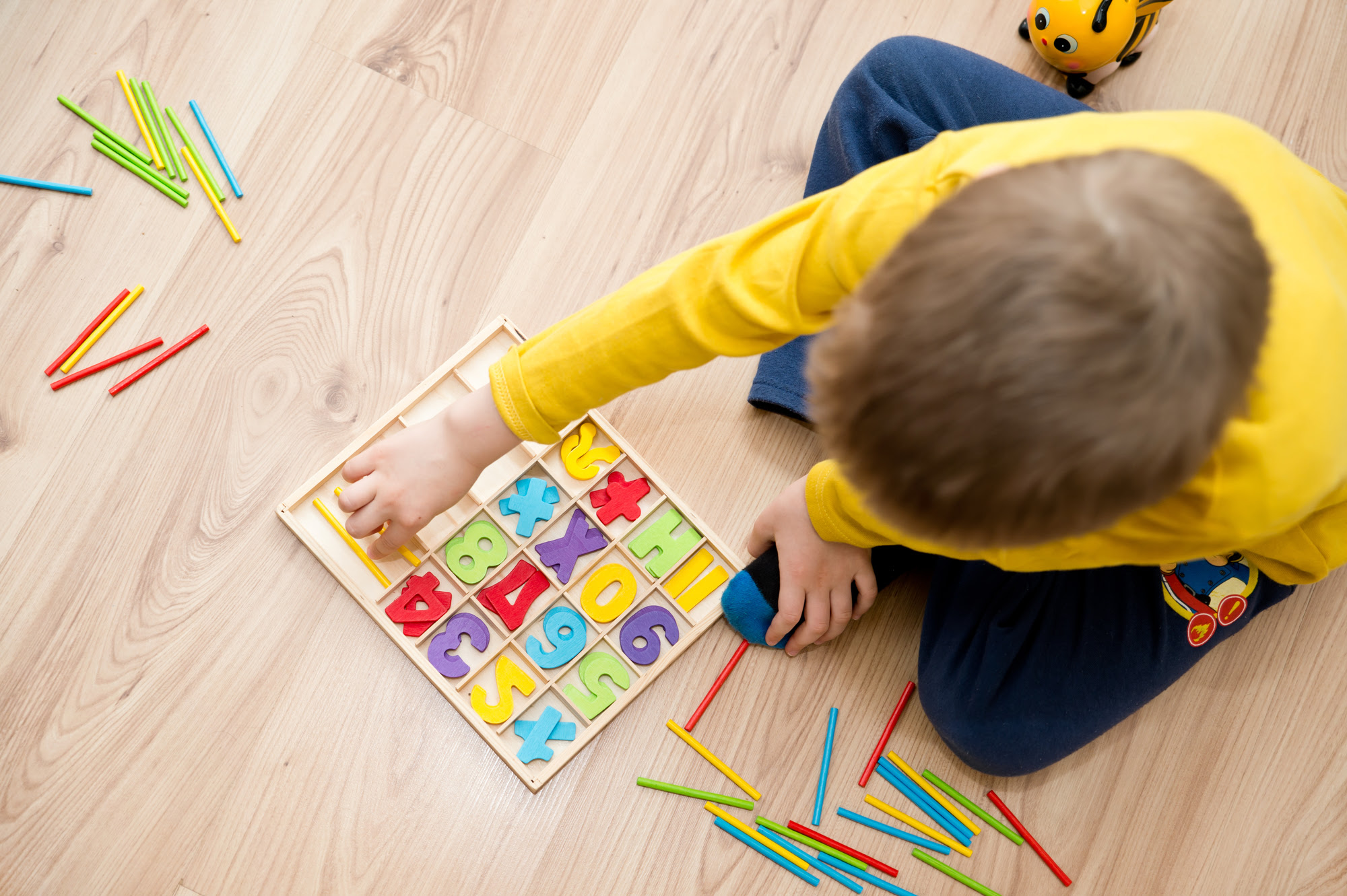 Un niño pequeño que juega con un sistema de conteo coloreado en el suelo.