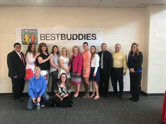 Superintendent Balow stands with participants and leaders from the Rawlins Best Buddies program underneath a big banner that reads, "Best Buddies".