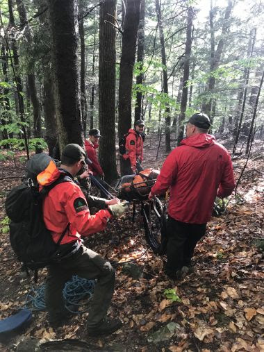 Rangers carrying injured hiker through the woods
