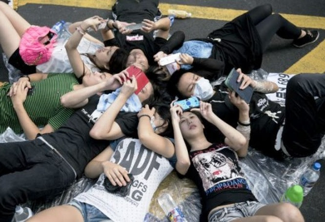 Jóvenes participantes en las protestas en Hong Kong utilizan sus teléfonos inteligentes para comunicarse