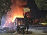 A person holds a sign as a Wendy&#39;s restaurant burns Saturday, June 13, 2020, in Atlanta after demonstrators set it on fire. Demonstrators were protesting the death of Rayshard Brooks, a black man who was shot and killed by Atlanta police Friday evening following a struggle in the Wendy&#39;s drive-thru line. (Ben GrayAtlanta Journal-Constitution via AP)