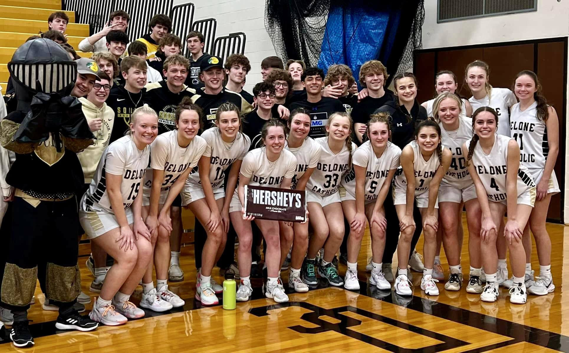 Girls' basketball team poses with fans after earning spot in district championship game