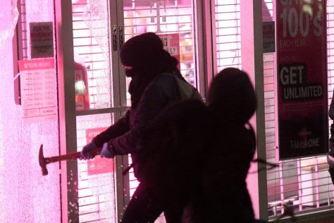 Los manifestantes rompen ventanas en una tienda T-Mobile durante una protesta contra el altavoz del campus