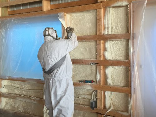 Working on insulating the walls of a home | Photo courtesy Halco Energy