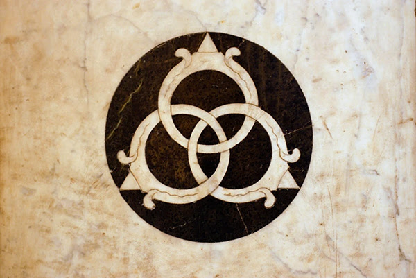 A white marble slab depicts a black circle with three light-coloured interlocked rings in its centre.