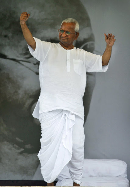 India's anti-corruption activist Anna Hazare greets his supporters, in front of a portrait of Mahatma Gandhi during the twelfth day of his hunger strike in New Delhi, India, Saturday, Aug. 27, 2011. (AP Photo/Rajesh Kumar Singh)