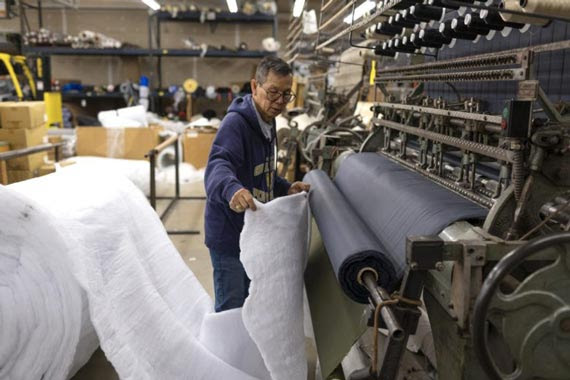 Kok feeding a large white roll of Lamilite material into two large rollers at the Wiggy's factory Kok feeding a large white roll of Lamilite material into two large rollers at the Wiggy's factory