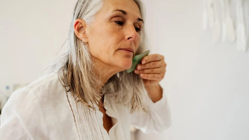 Older woman using gua sha skin scraping on jaw