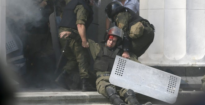 Varios agentes retiran a un compañero herido durante los enfrentamientos en Kiev. - REUTERS